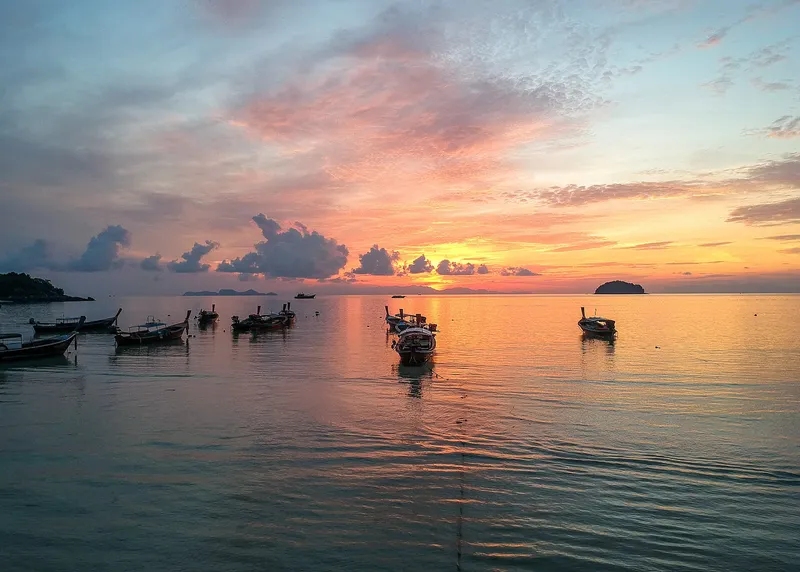 Sunrise over the sea from Koh Lipe, longtail boats in the foreground