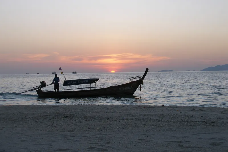 Longtail boat coming in to a Koh Lipe beach at sunset