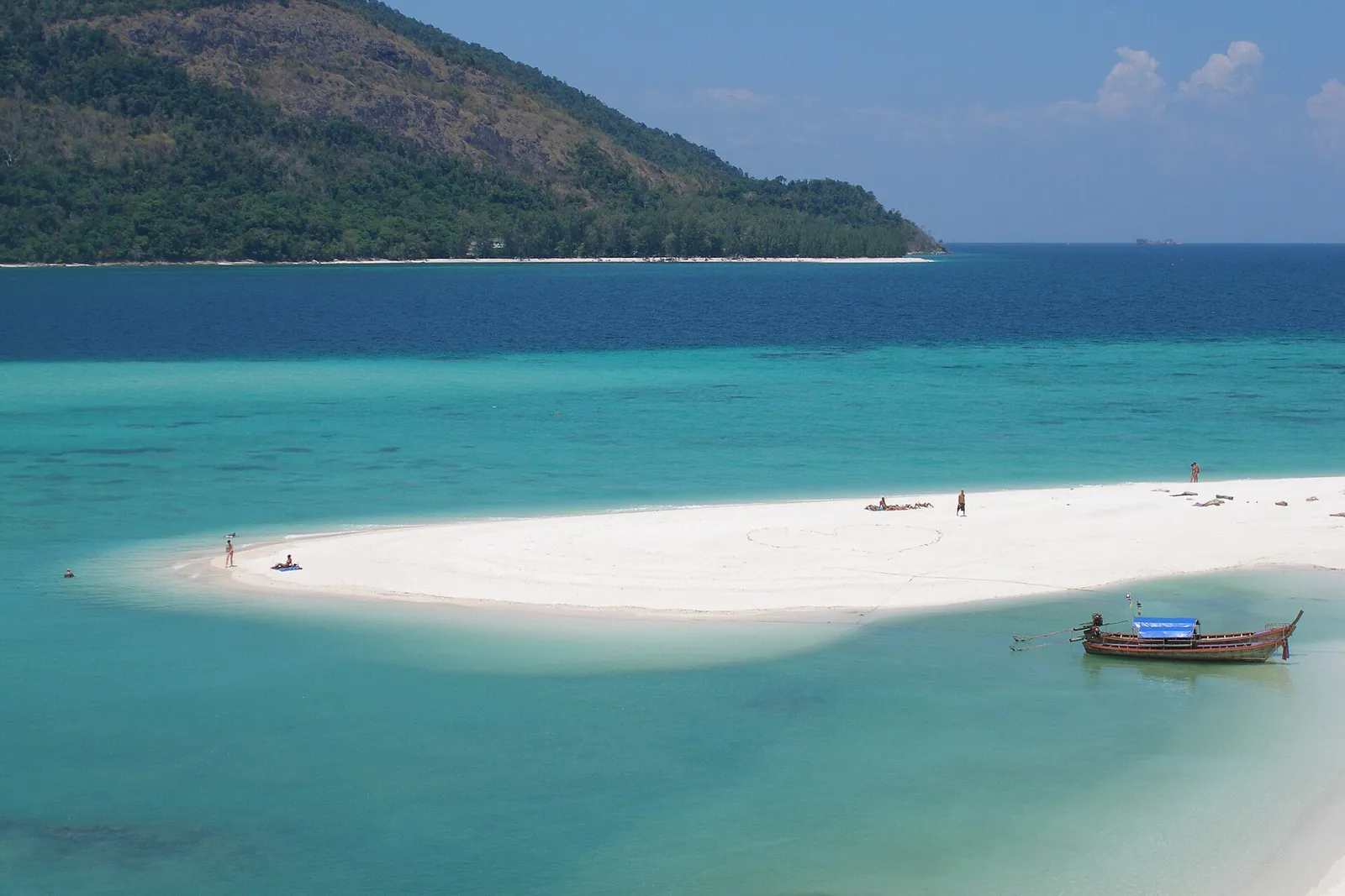 Longtail boat beside the white sandbar on Koh Lipe, with Koh Adang behind