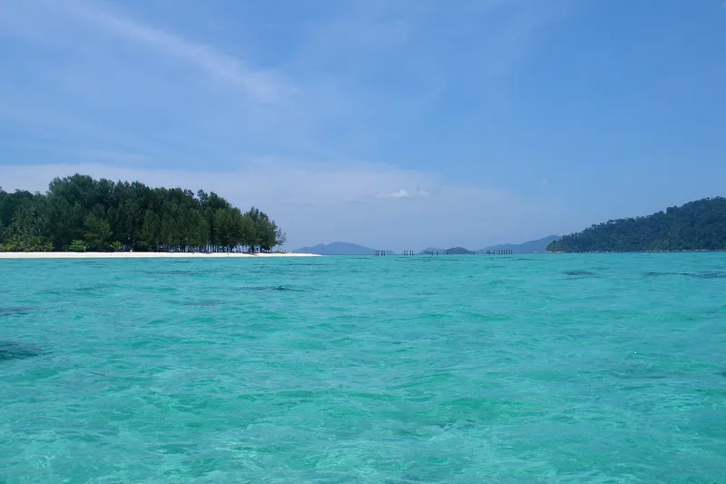 Shallow turquoise water between Koh Lipe and Koh Adang, with a small wooded islet