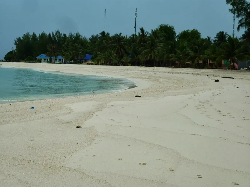 White sand beach and palm trees on Koh Lipe under a grey sky